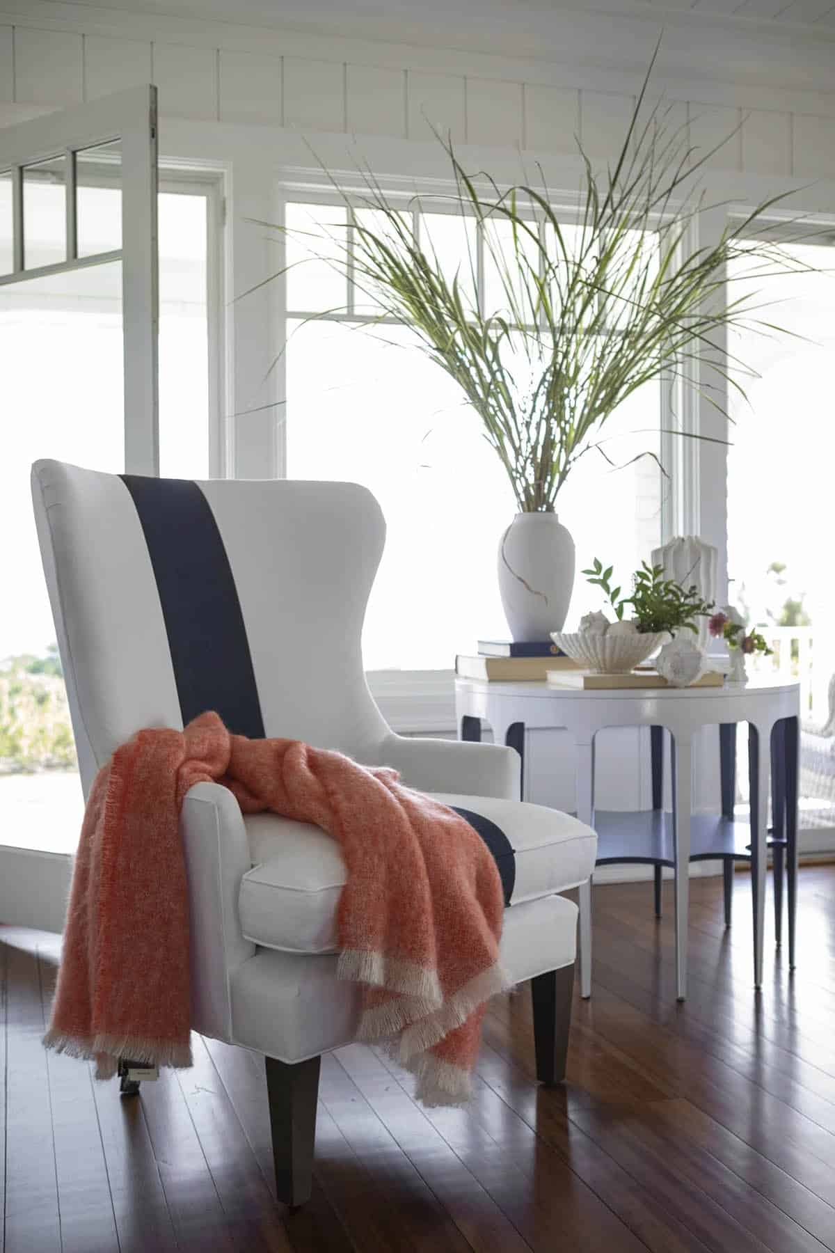 Navy striped wingback chair with coral throw and side table