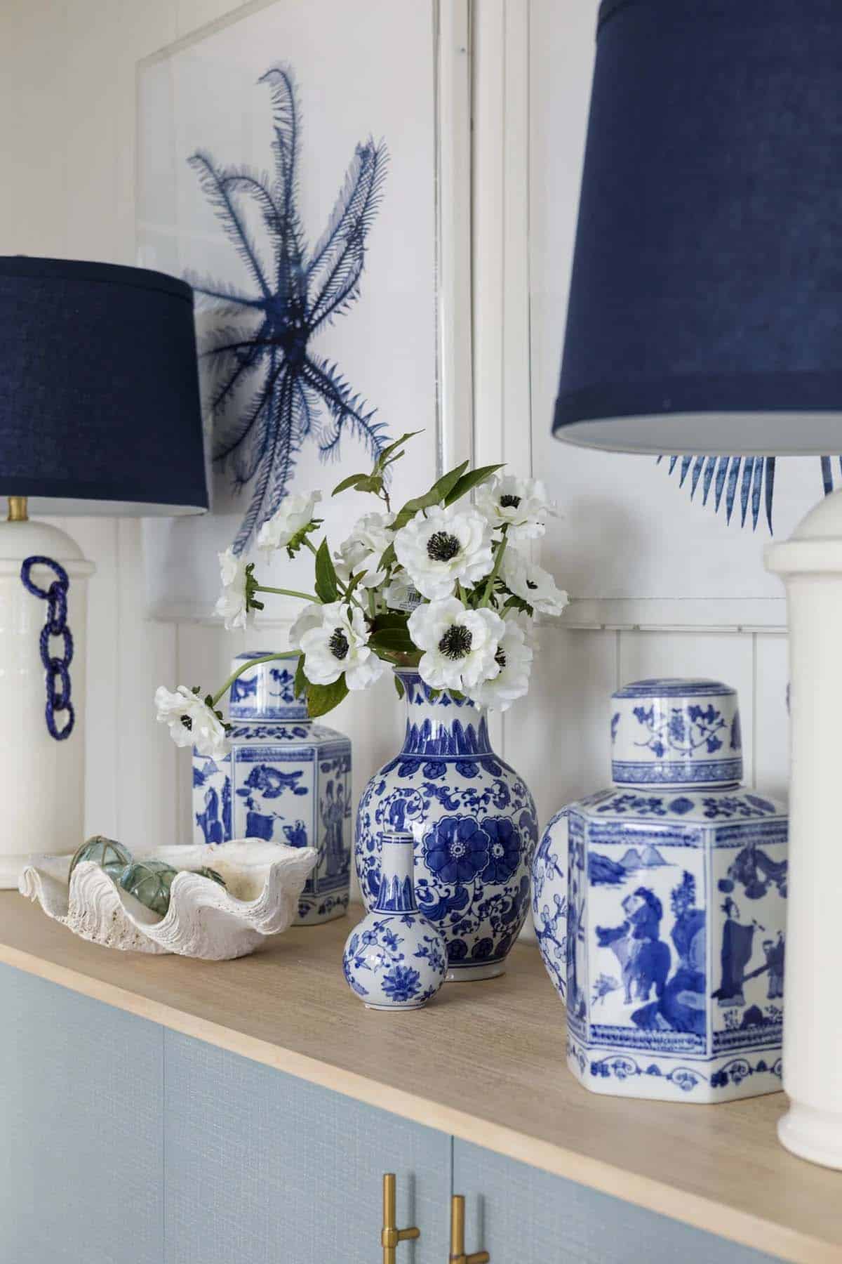 Blue and white ceramics grouped beneath navy drum lampshades