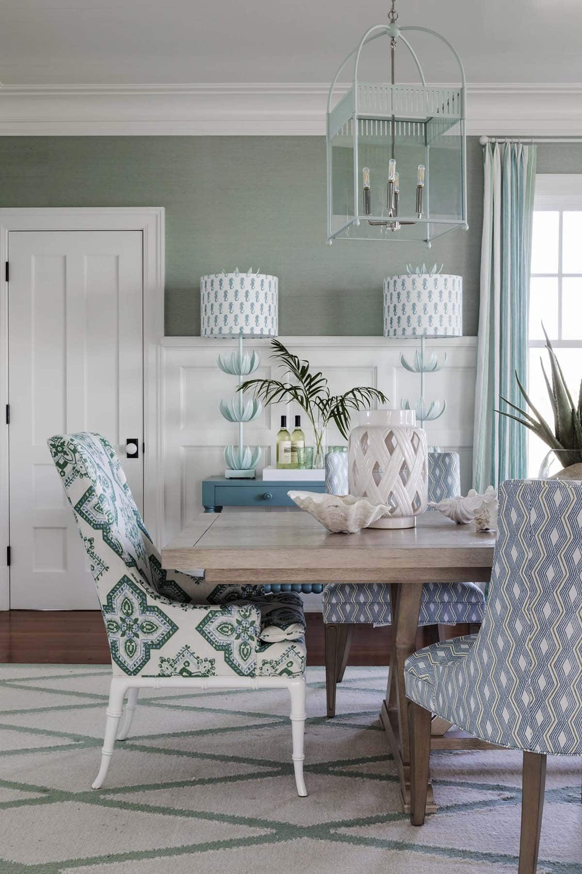 Green wallpapered dining room with patterned chairs and seahorse lamps