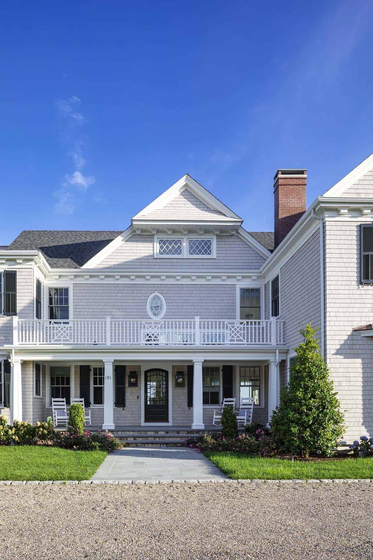 Symmetrical facade of shingle-style home with brick chimney