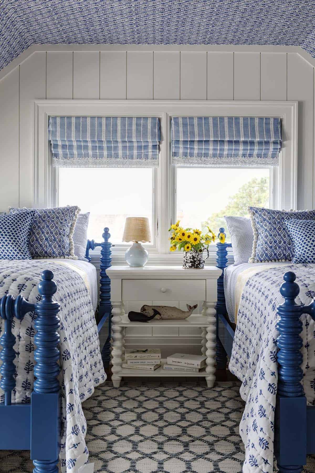 Twin beds flanking white nightstand with sunflowers in pitcher