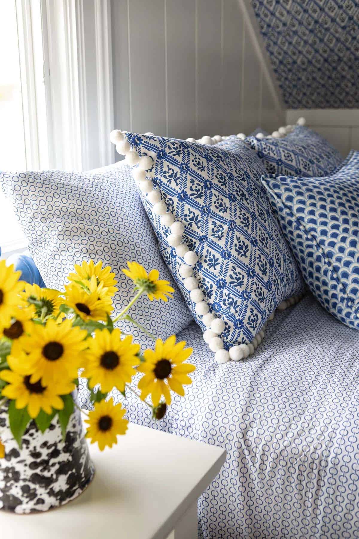 Blue and white pom-pom trimmed pillows beside sunflower bouquet