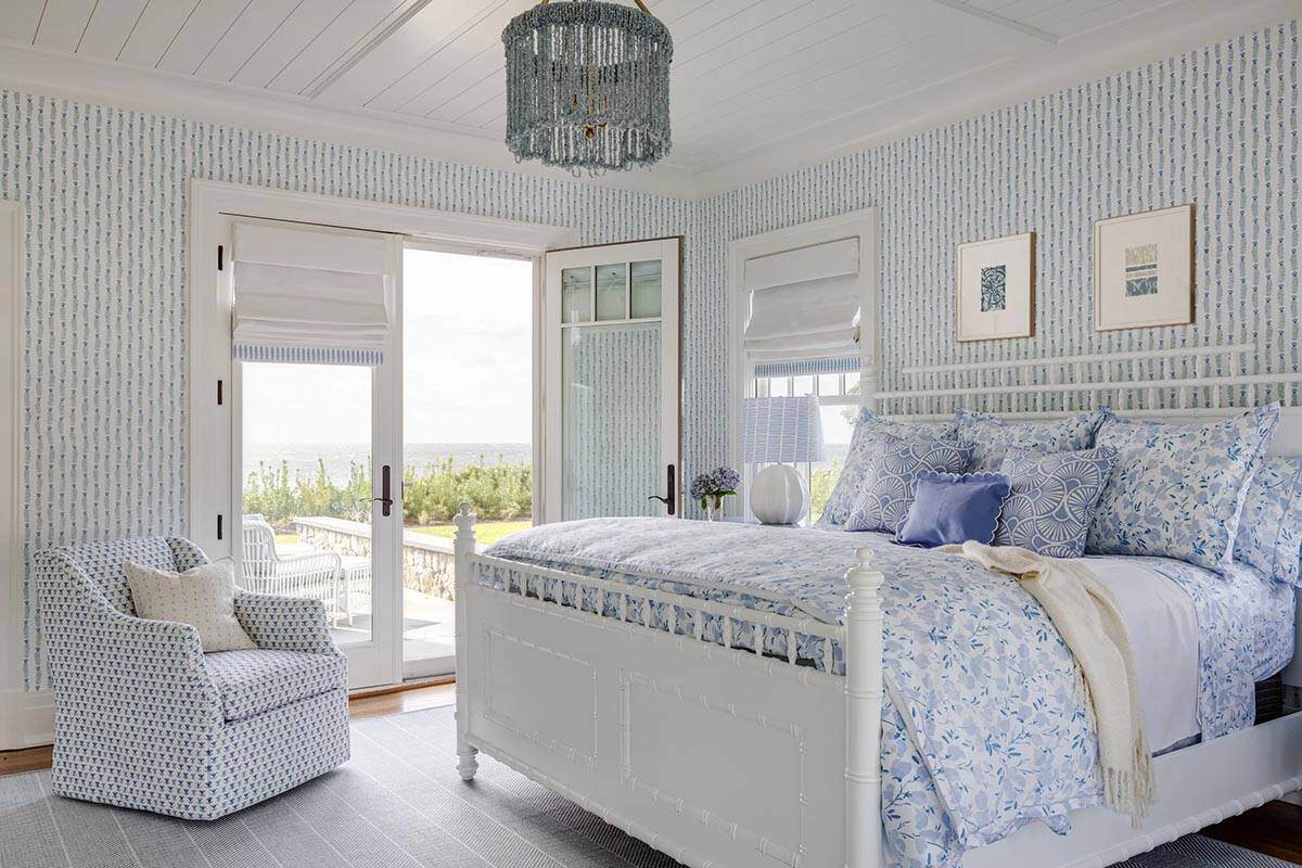 White bedroom with beaded chandelier and ocean-facing French doors
