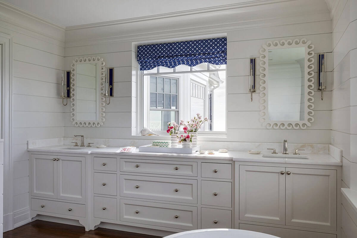 Double vanity bathroom with scalloped mirrors and blue roman shade
