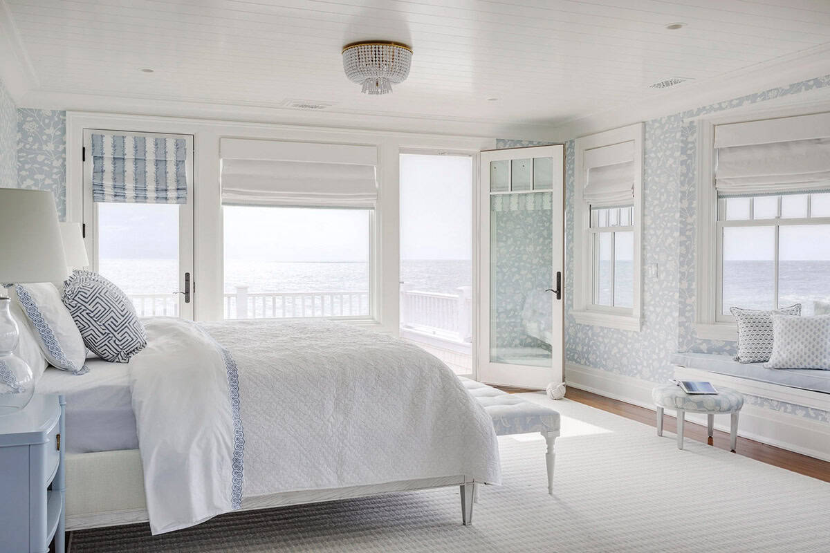 Pale blue bedroom with white bedding and ocean-view balcony doors