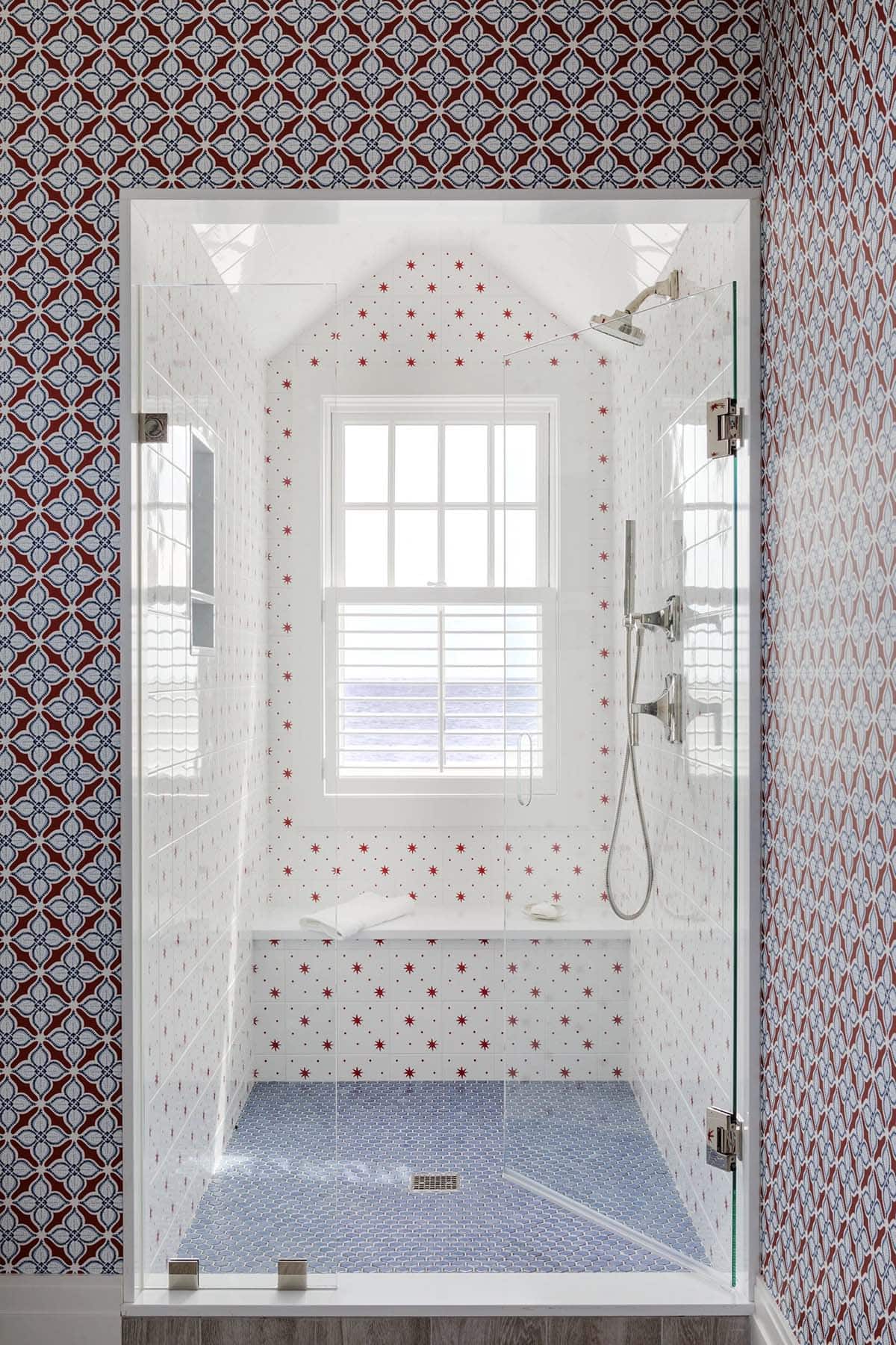 Star-tiled shower with red accents facing an ocean-view window
