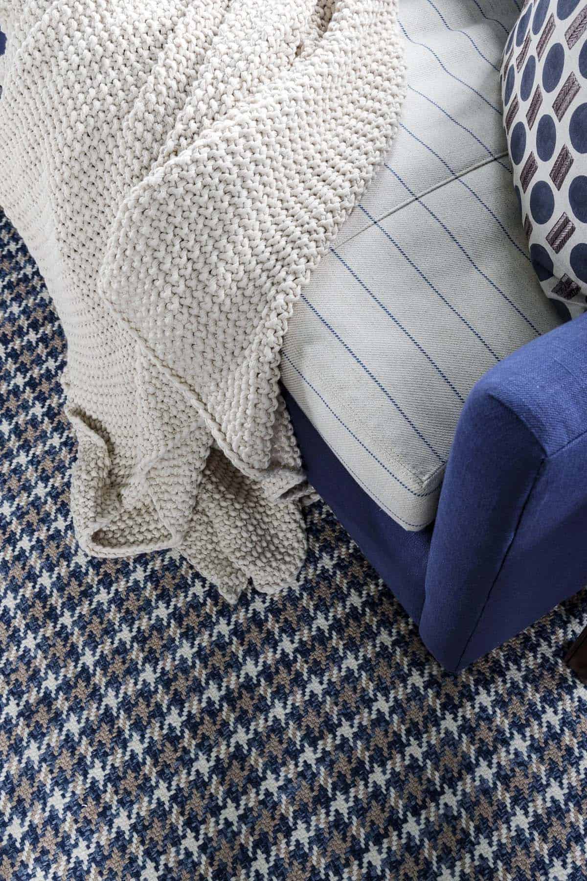 Close-up of houndstooth rug beneath navy sofa and throw