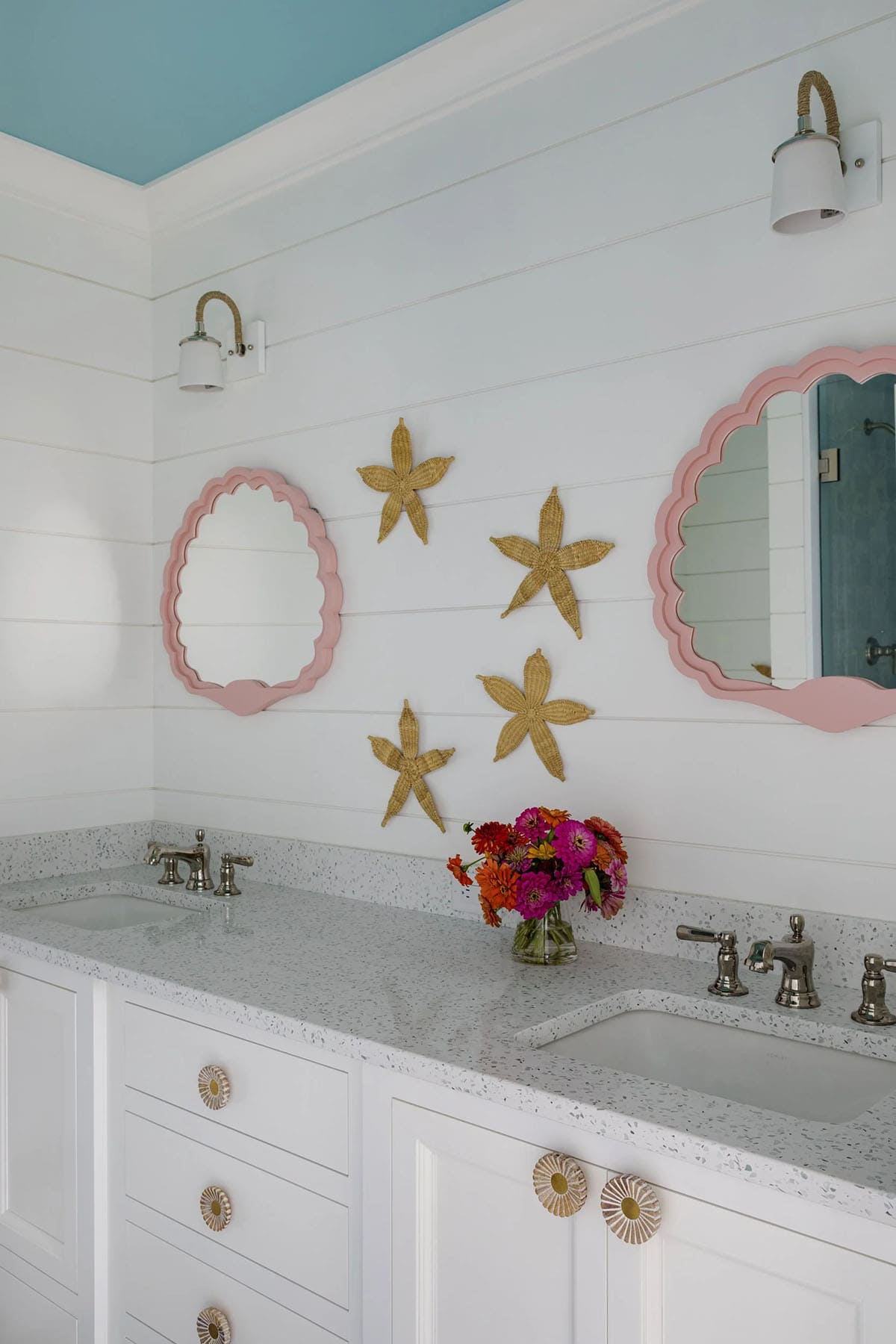 Pink scalloped mirrors flanked by woven starfish wall decor