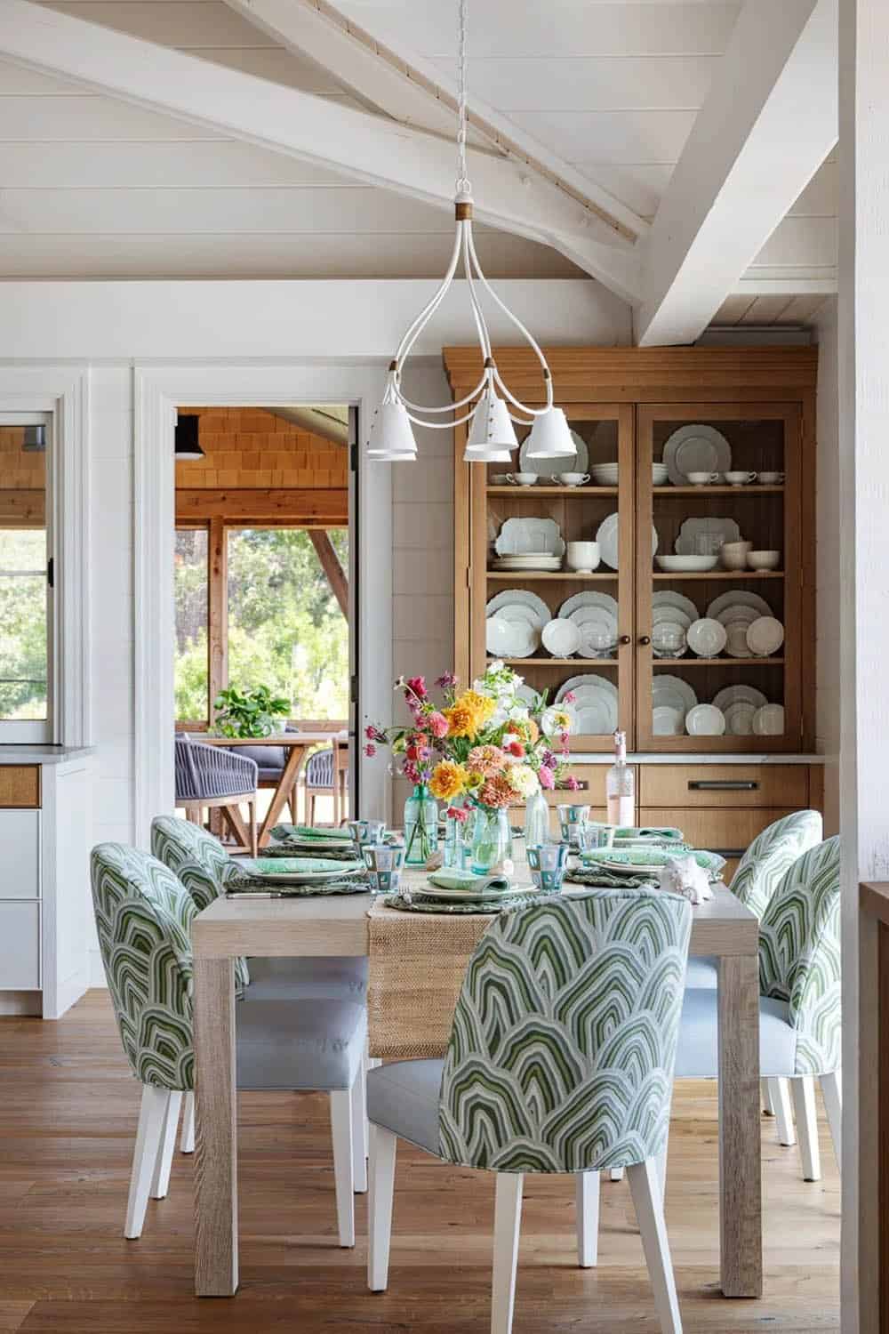 Dining room with patterned green chairs, wildflower centerpiece, and built-in china cabinet