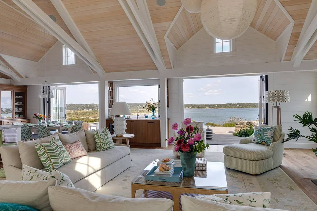 Open-concept great room with vaulted beamed ceiling and folding walls to bay view
