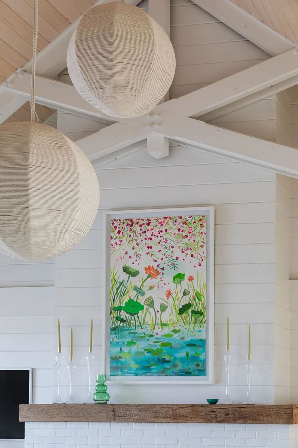 Woven pendant lights hanging near floral artwork above fireplace mantel