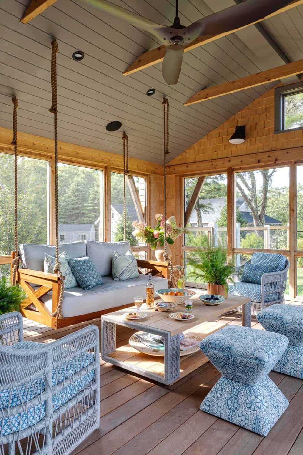Screened porch with hanging rope swing sofa and blue patterned cushions