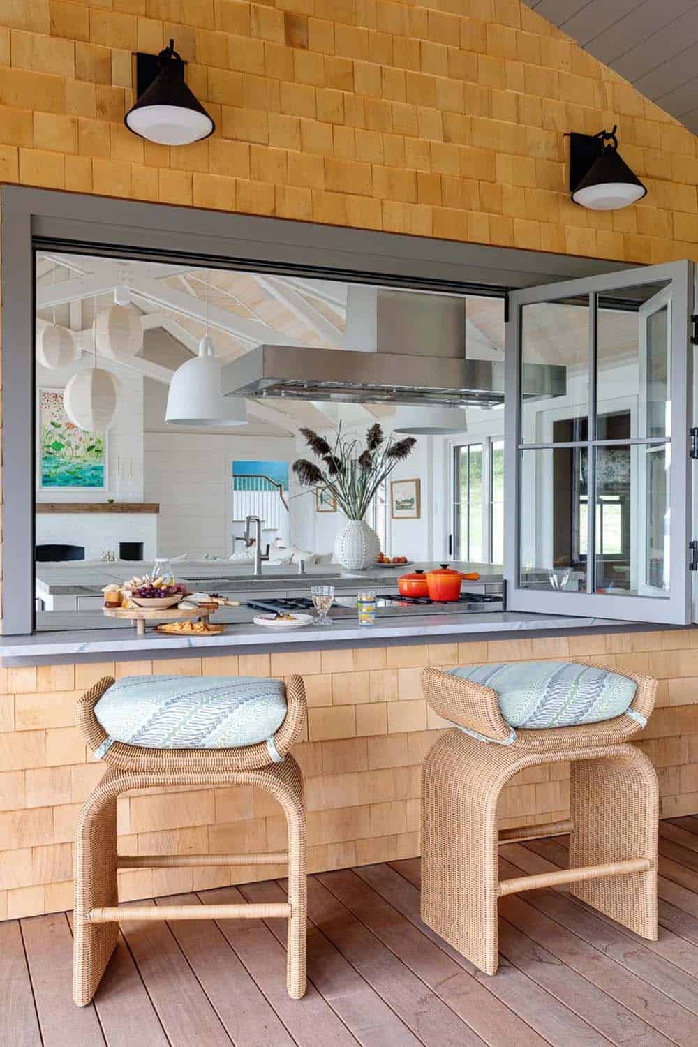 Pass-through kitchen window with rattan stools on porch overlooking dining area