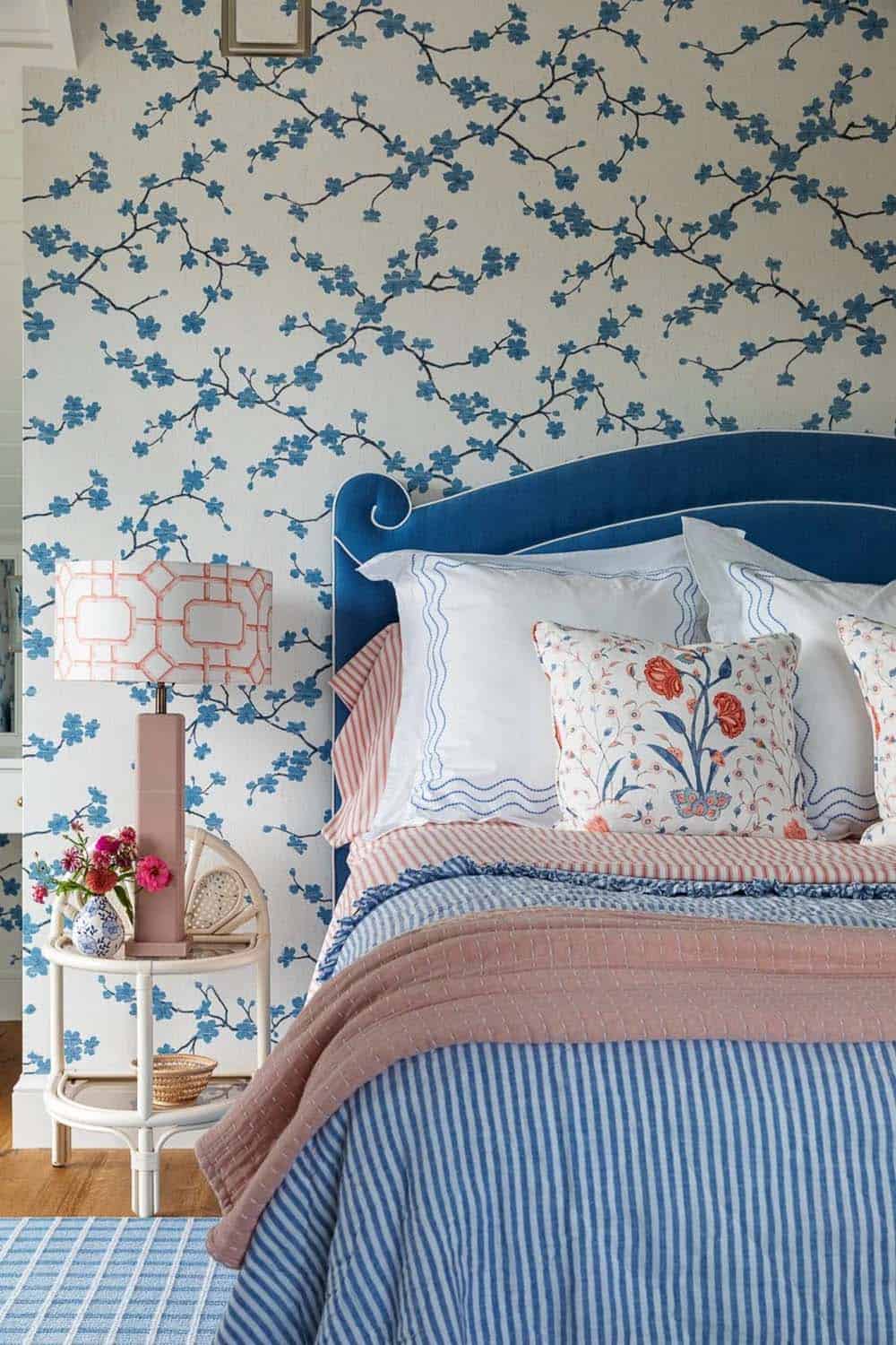 Bedroom bed detail with blue scalloped headboard against blue cherry blossom wallpaper