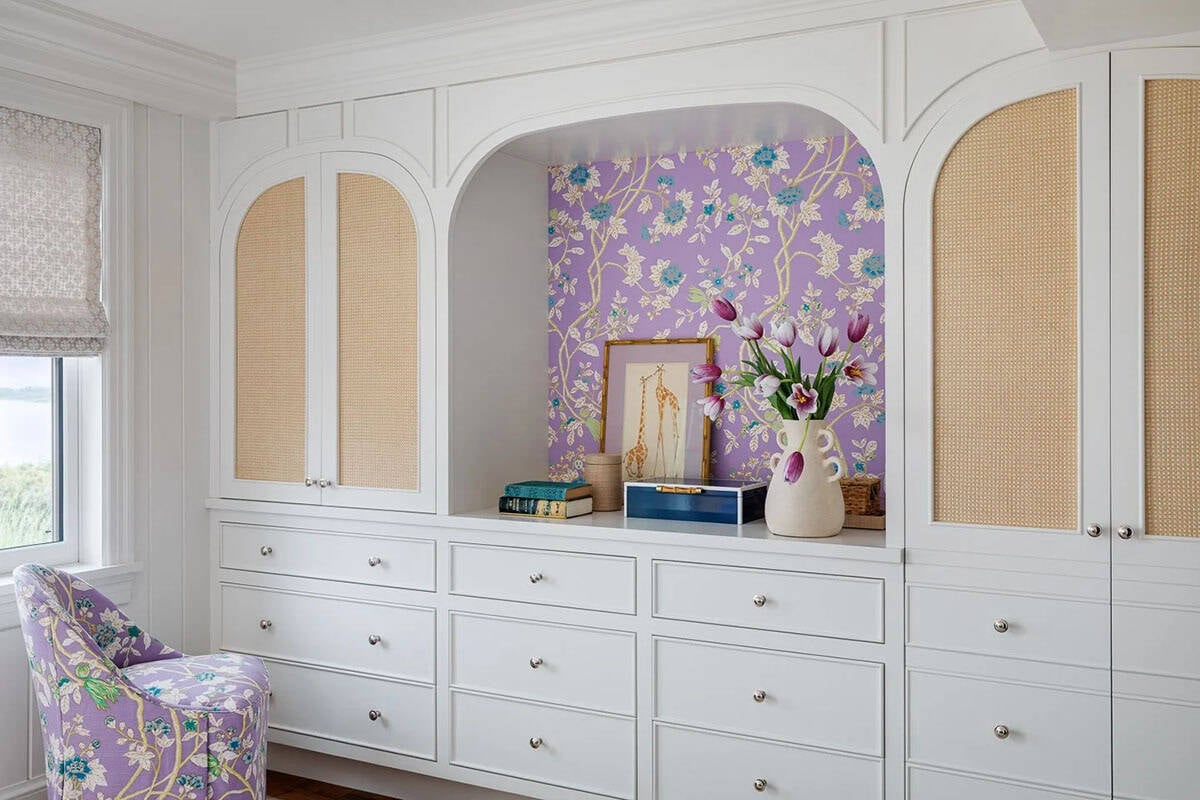 Built-in white cabinetry with purple floral wallpaper alcove and cane door panels