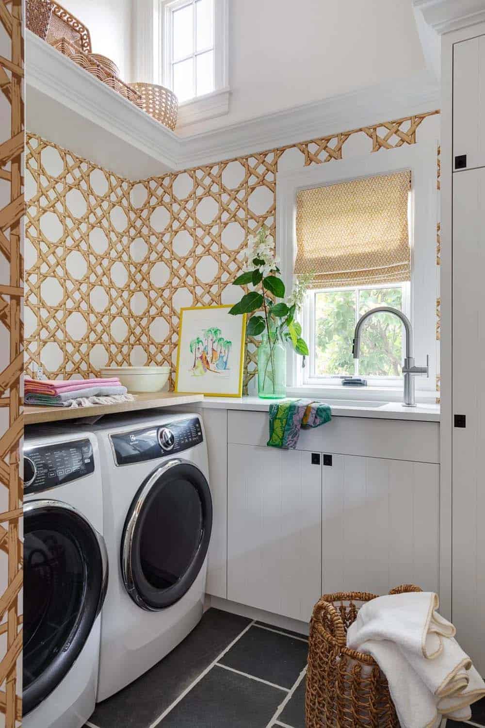 Laundry room with cane-lattice wallpaper, front-load washer/dryer, and floral art