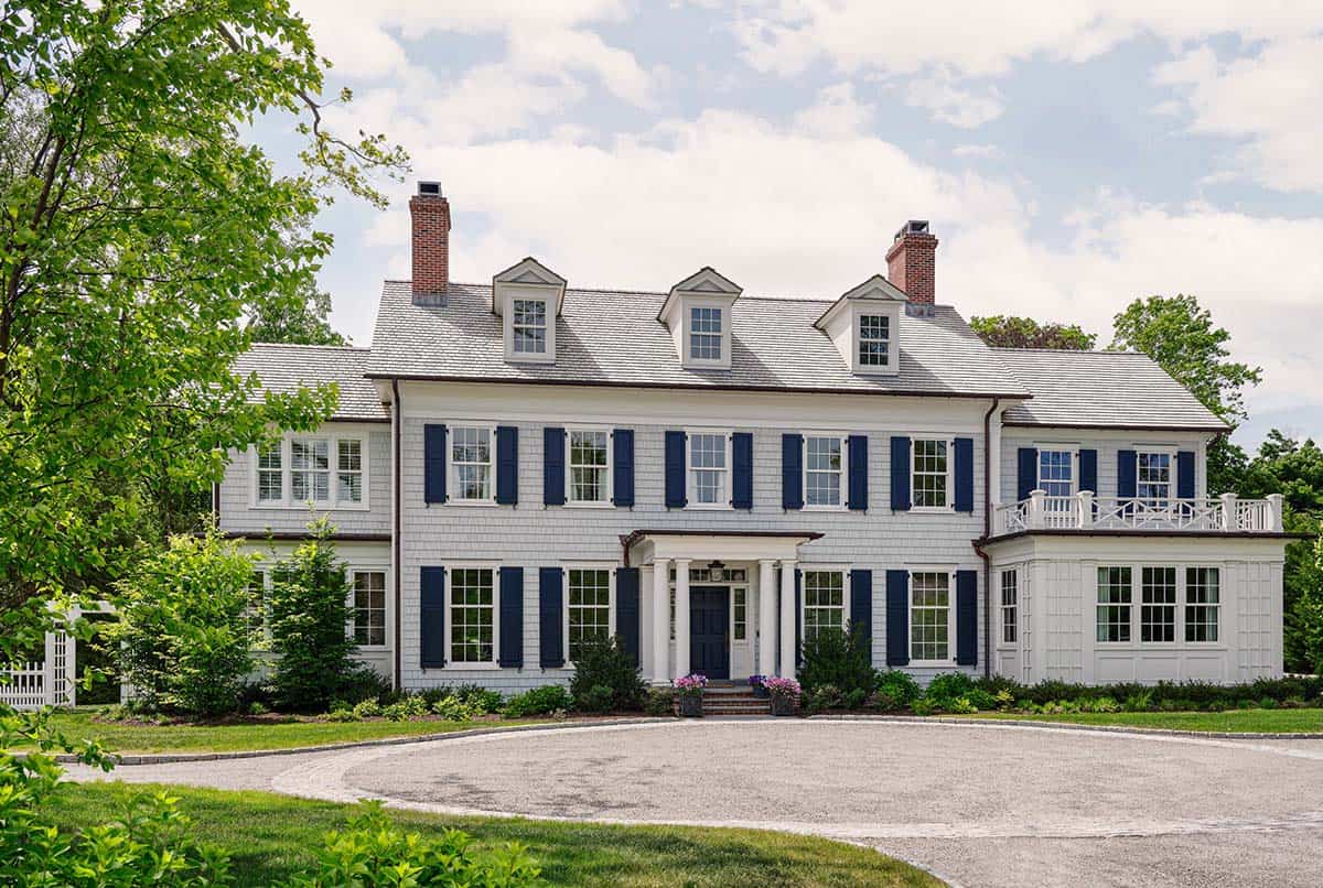 White shingle colonial revival house with navy blue shutters and dormer windows