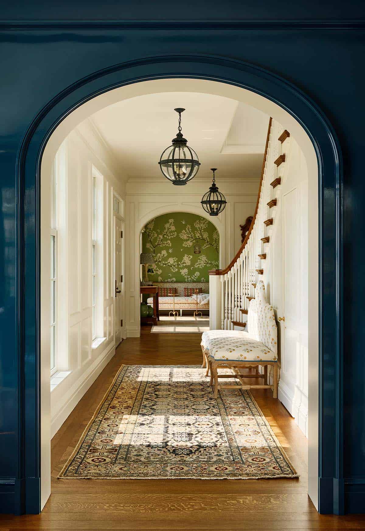 Hallway with navy arched doorway and antique runner rug leading to staircase