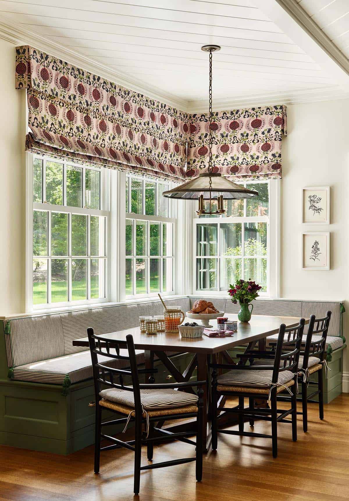 Breakfast nook with striped banquette seating and floral roman shades