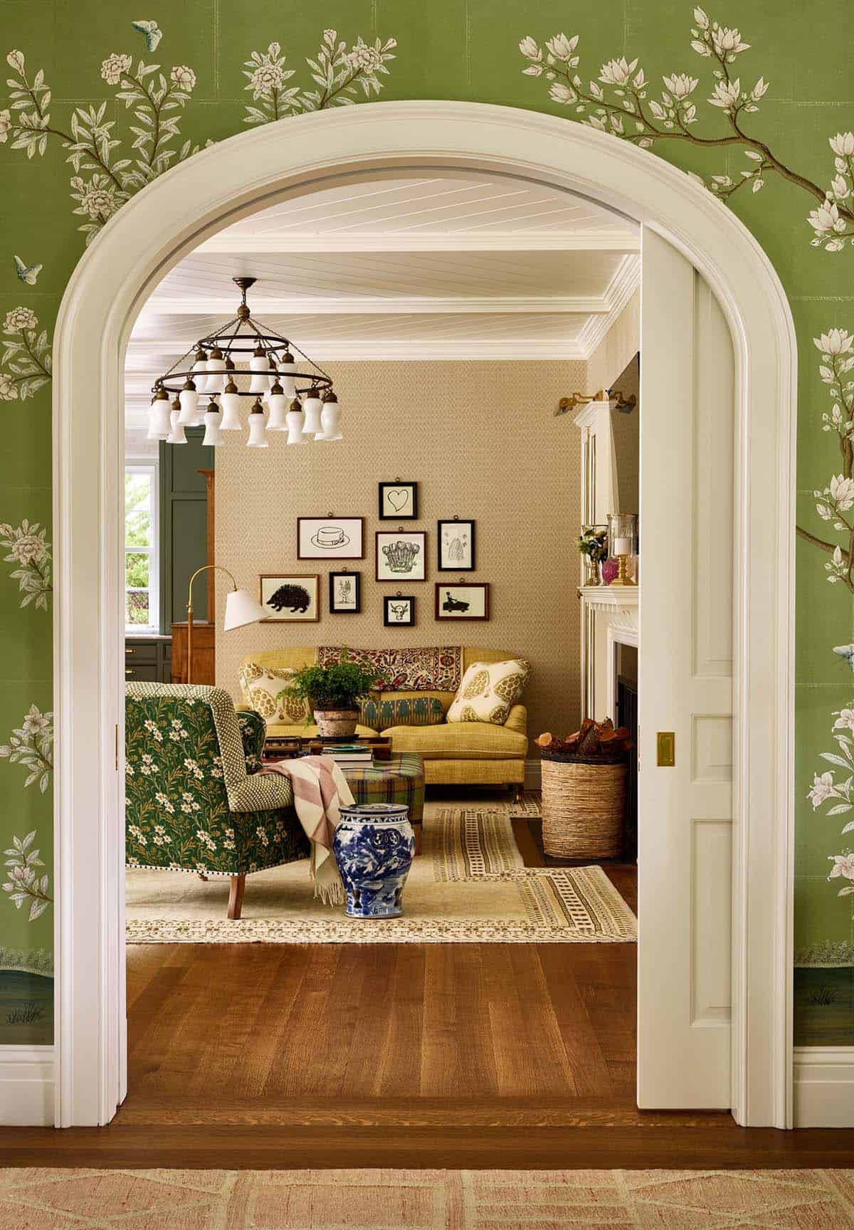 Living room seen through arched doorway with green chinoiserie wallpaper