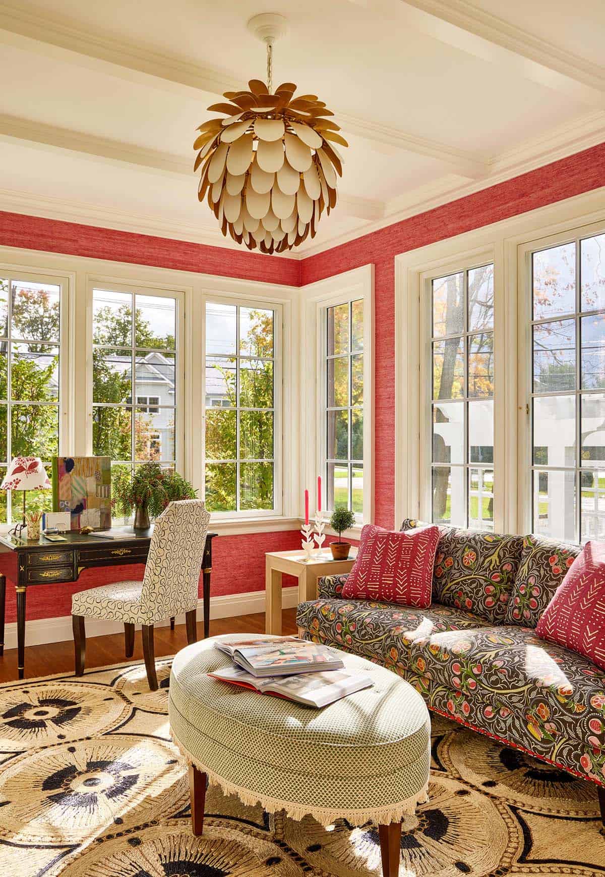 Sunroom home office with red grasscloth walls and patterned sofa