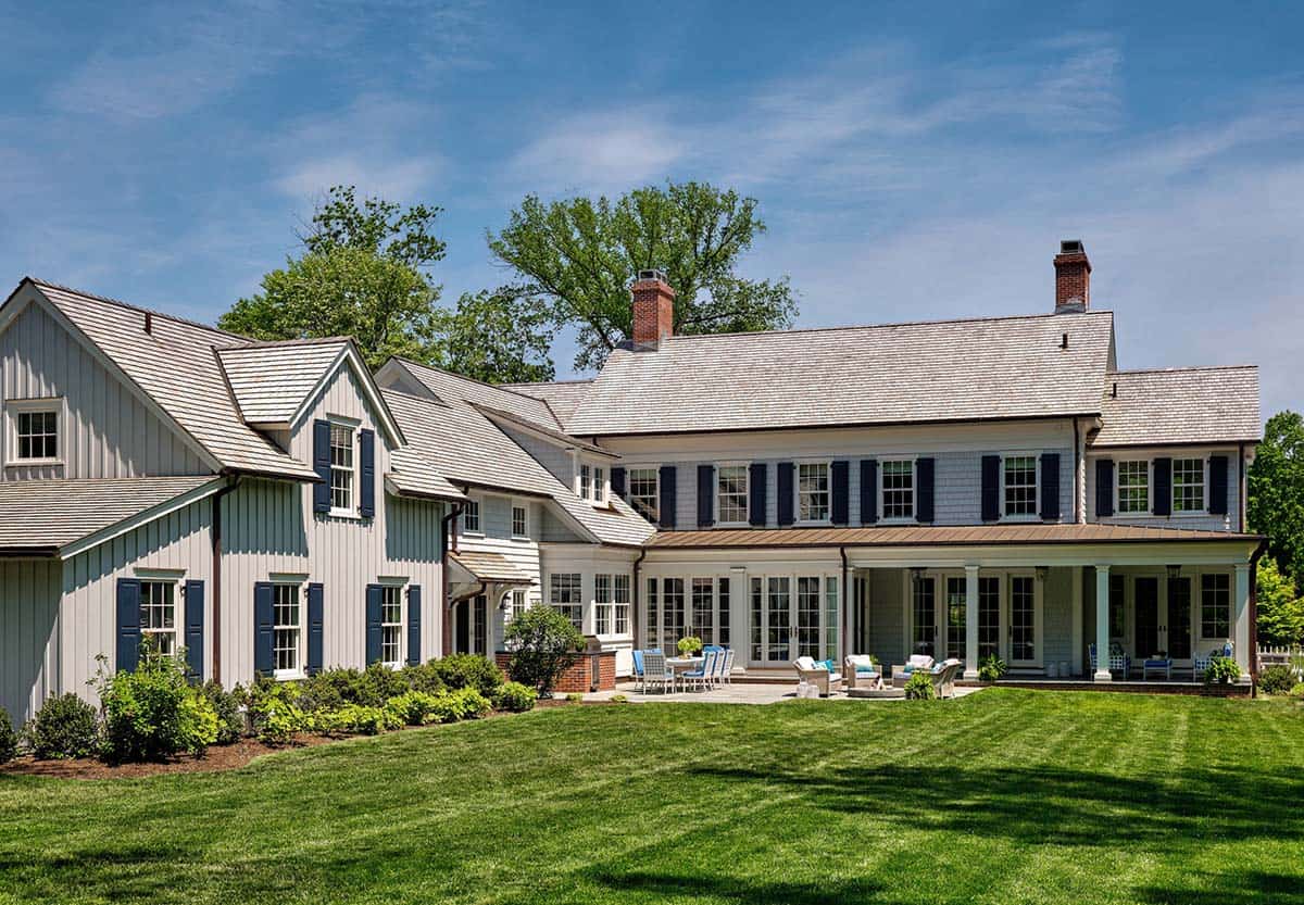 Back view of shingle-style home with multiple gables and stone patio
