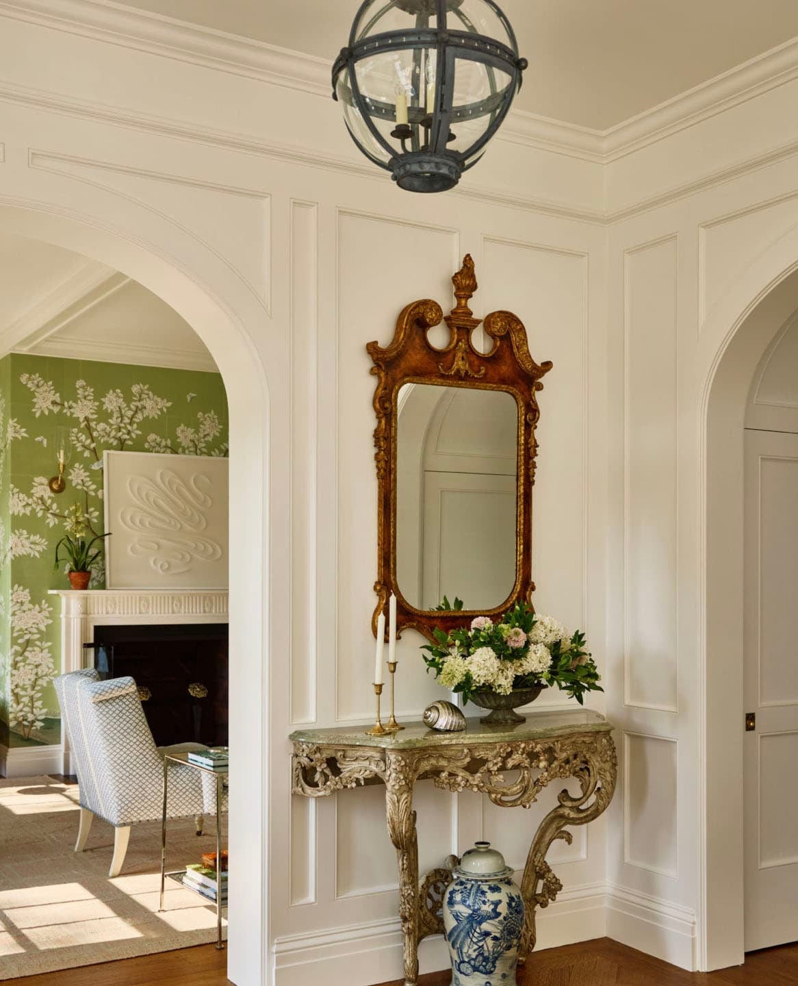 Foyer vignette with antique gilt mirror and carved console table