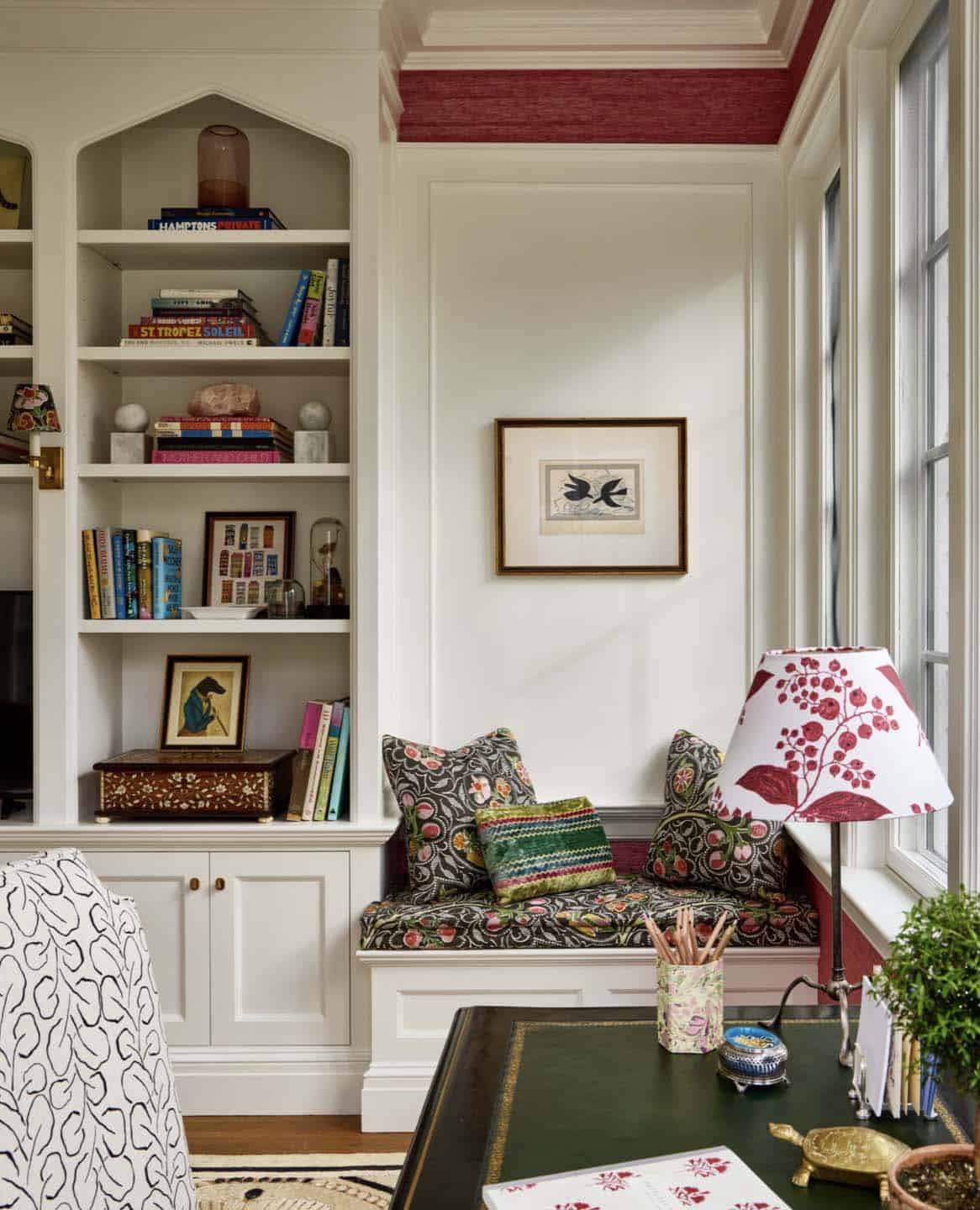 Home office reading nook with built-in bookshelves and floral cushions