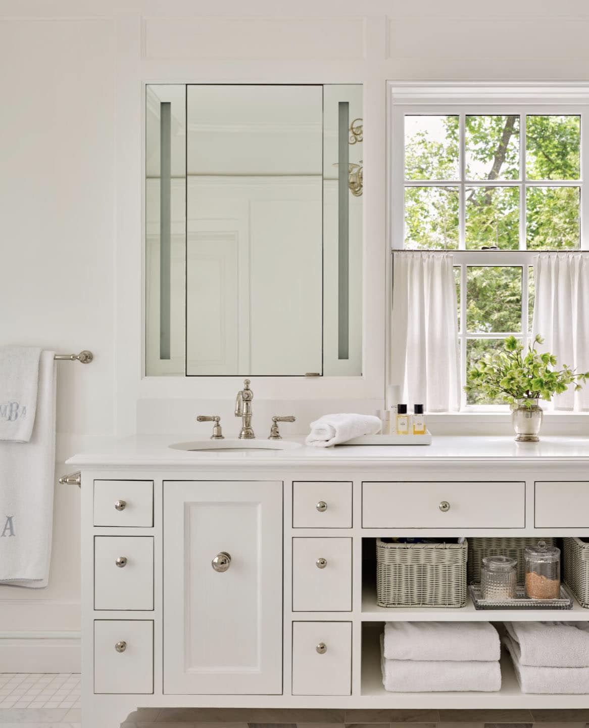 White primary bathroom vanity with double sinks and wicker storage baskets