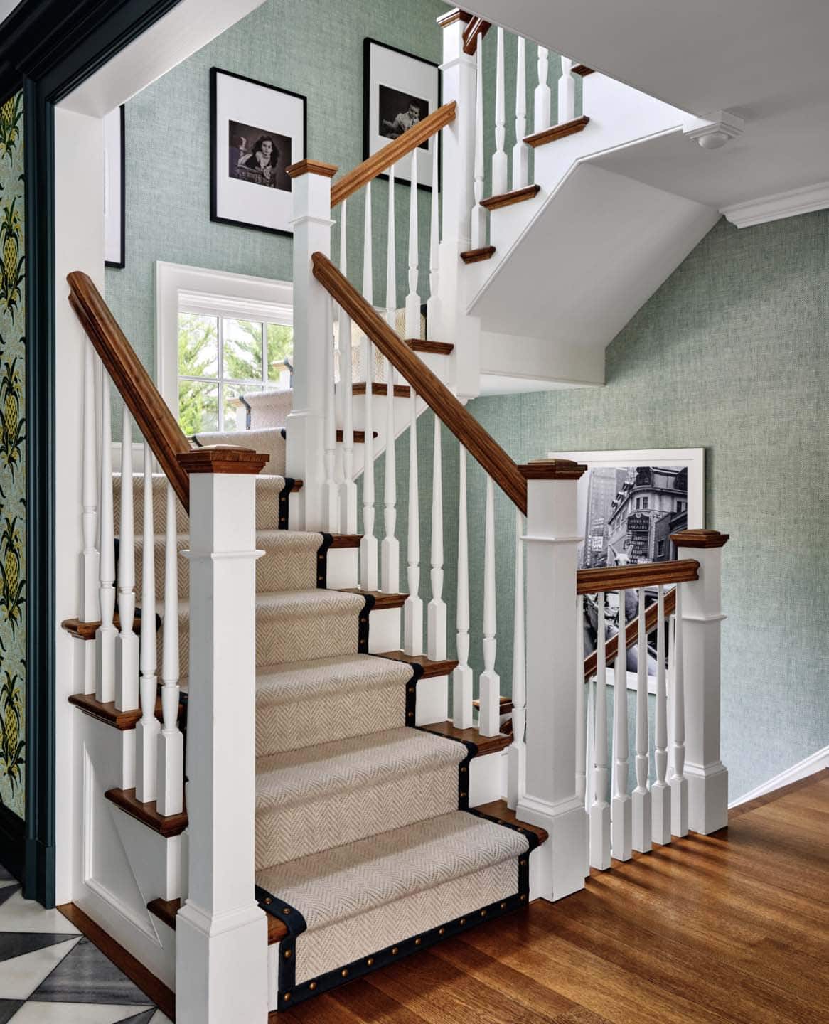 Staircase with herringbone runner and seafoam grasscloth wallpaper