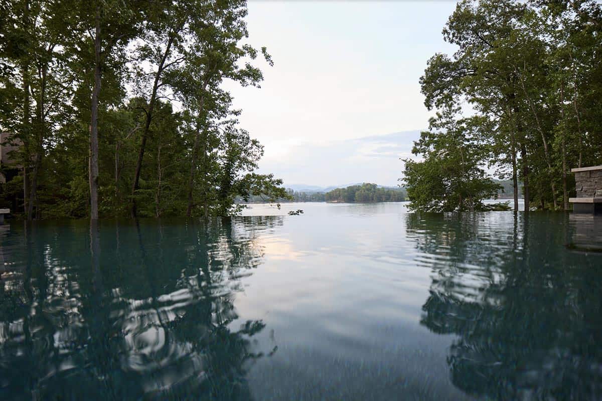 Infinity pool edge overlooking Lake Keowee with tree-lined shore and mountains in the distance