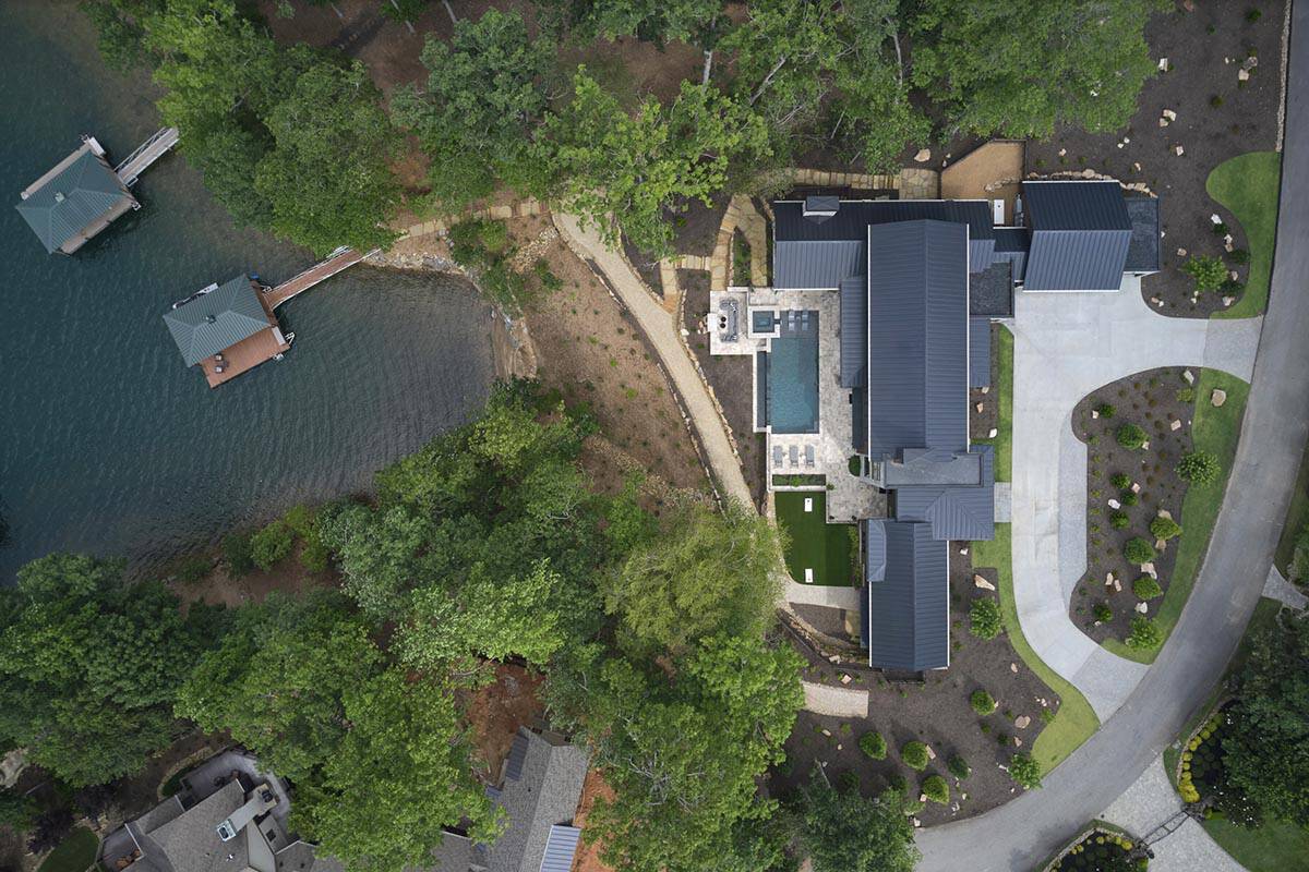 Aerial view of the lakefront property showing the house, pool, boat docks, and wooded lot