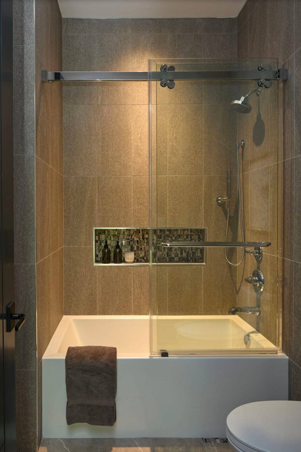 Bathroom shower-tub combo with sliding glass door, tiled walls, and a mosaic niche