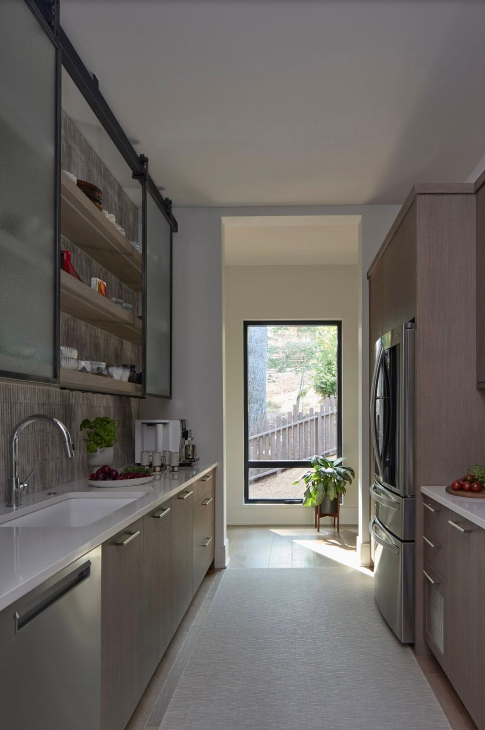 Butler's pantry with sliding glass cabinet, stainless refrigerator, and a view down a hallway
