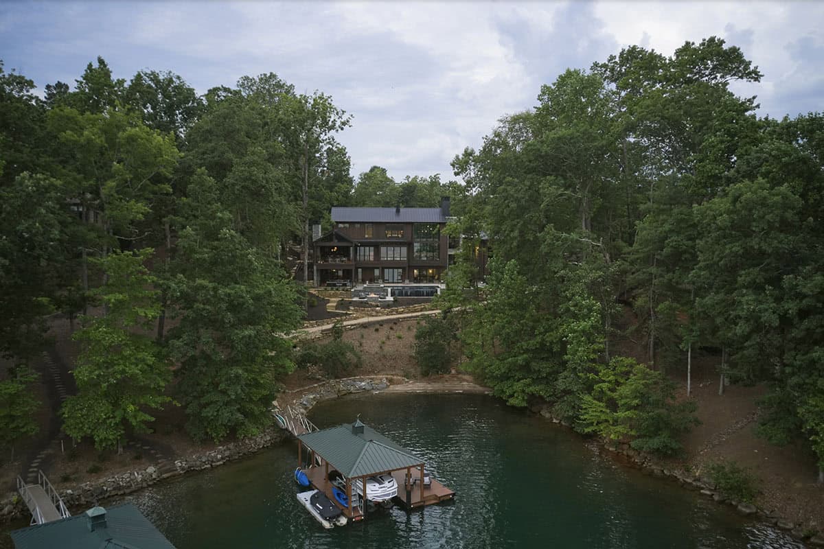 Aerial view of the wooded property with lake cove, boat dock, and house nestled among trees