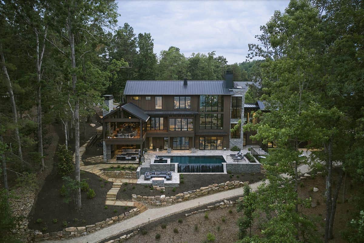 Aerial view of the three-story lake house with pool, patio, and stone landscape walls