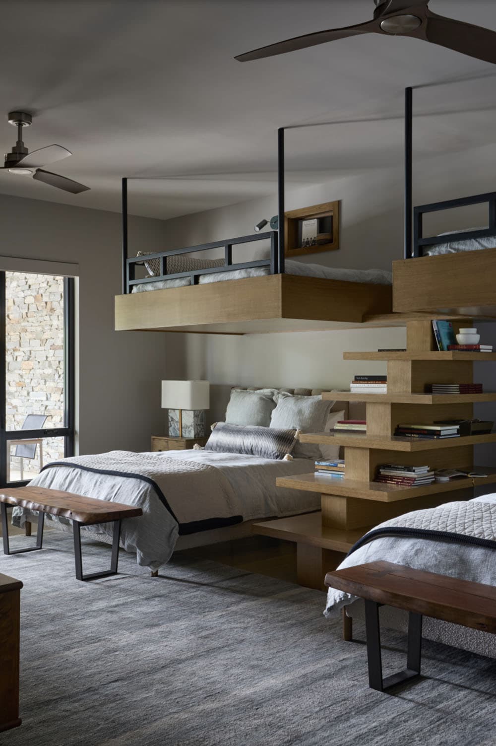 Bunk-style bedroom with suspended metal-frame beds and built-in bookshelf steps