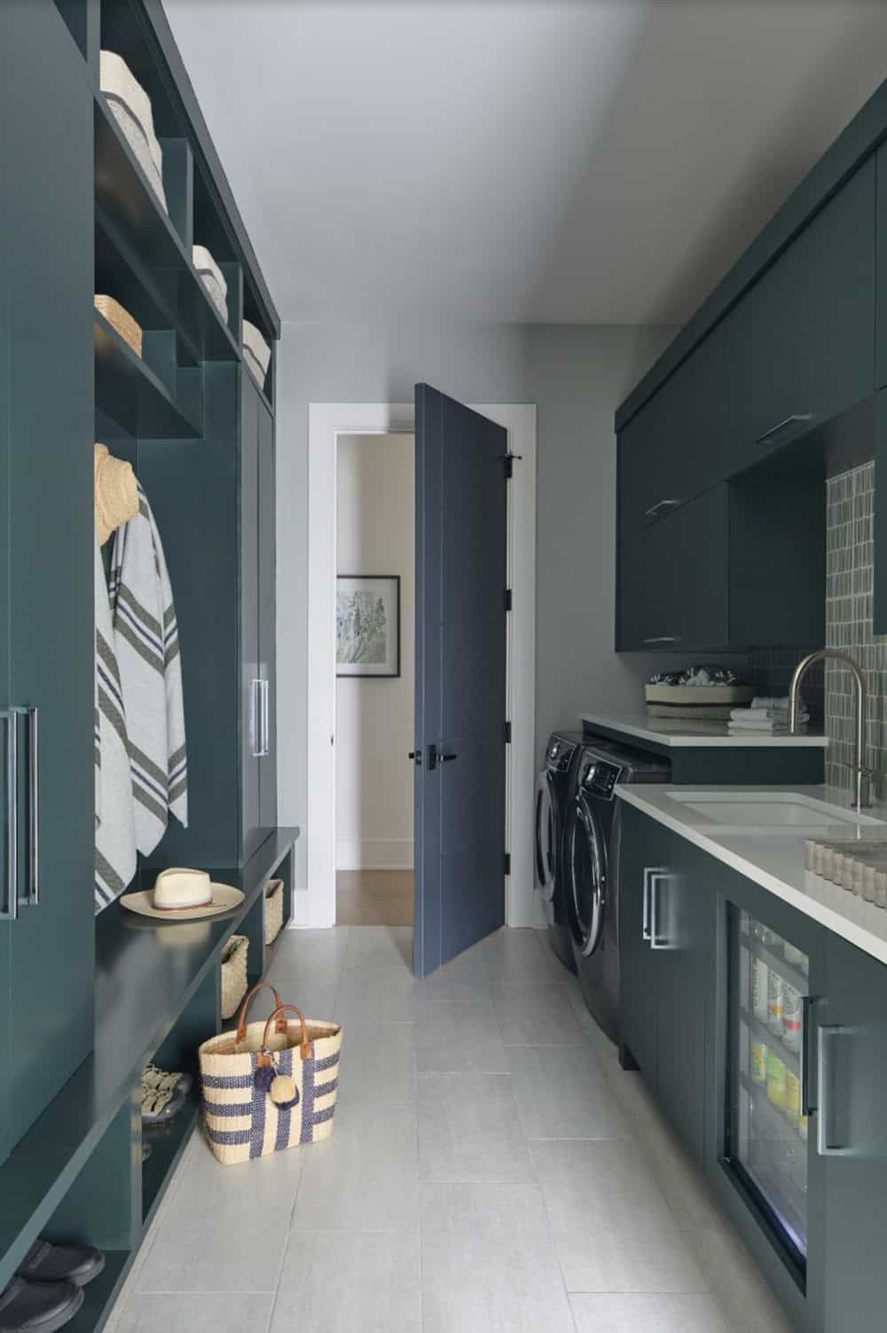 Mudroom and laundry room with dark green cabinetry, washer/dryer, and woven baskets