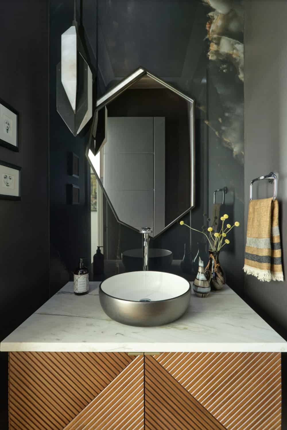 Dark powder room with hexagonal mirror, vessel sink, marble counter, and fluted wood vanity