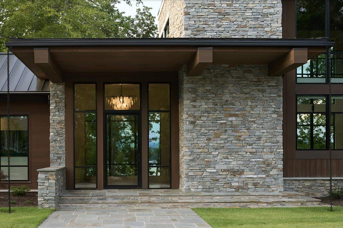 Close-up of the front entrance with glass sidelights, pendant chandelier, and stacked stone walls