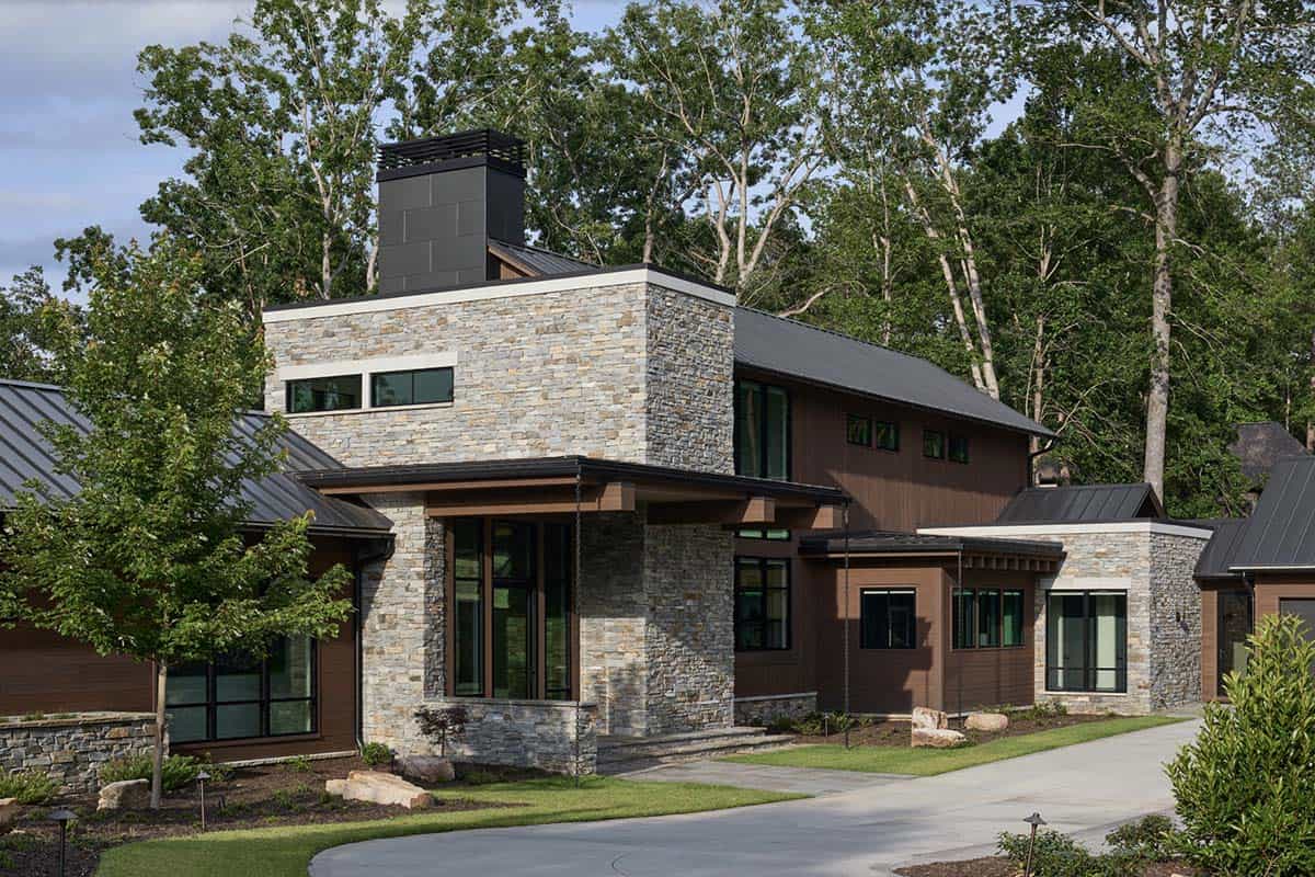 Corner view of the stone entry tower and dark wood siding with covered porch