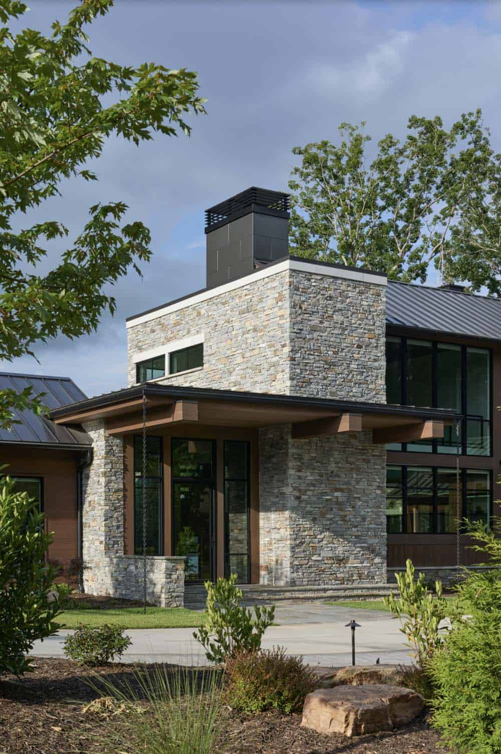 Front stone entry tower with covered porch, chimney, and landscaped foundation beds