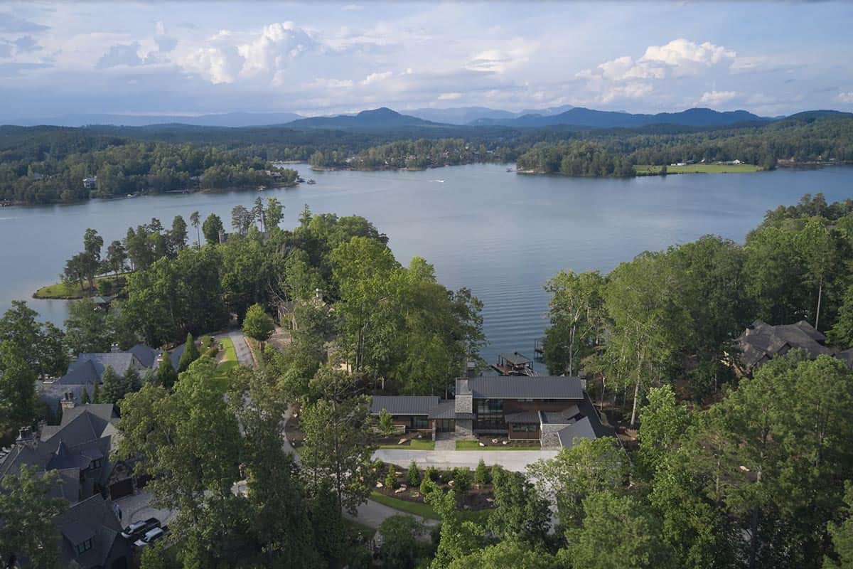 Aerial view of the house nestled among trees along the lake's shoreline with boat dock