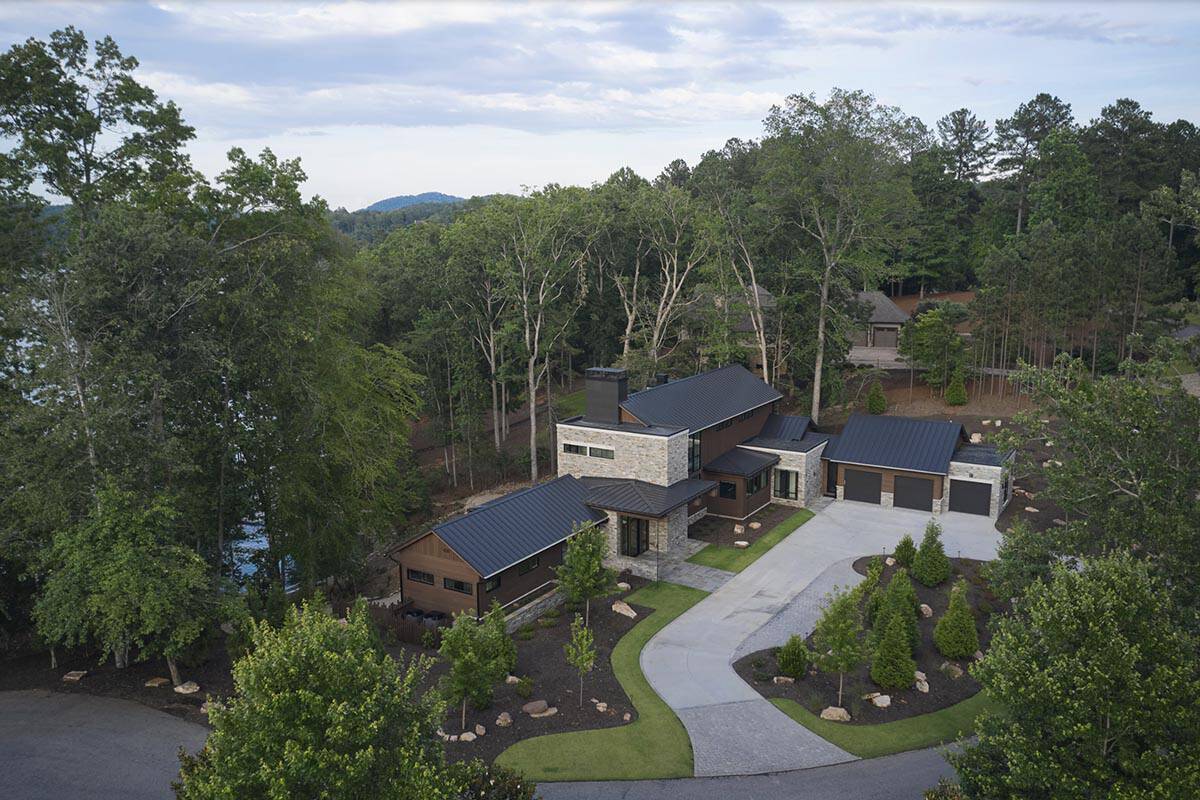 Aerial view of the full property showing house, garage, driveway, and surrounding woods