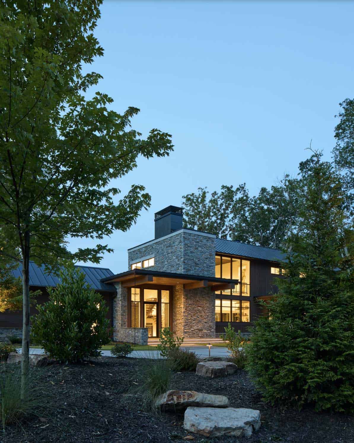 Twilight view of the stone entry tower with glowing interior lights through the windows