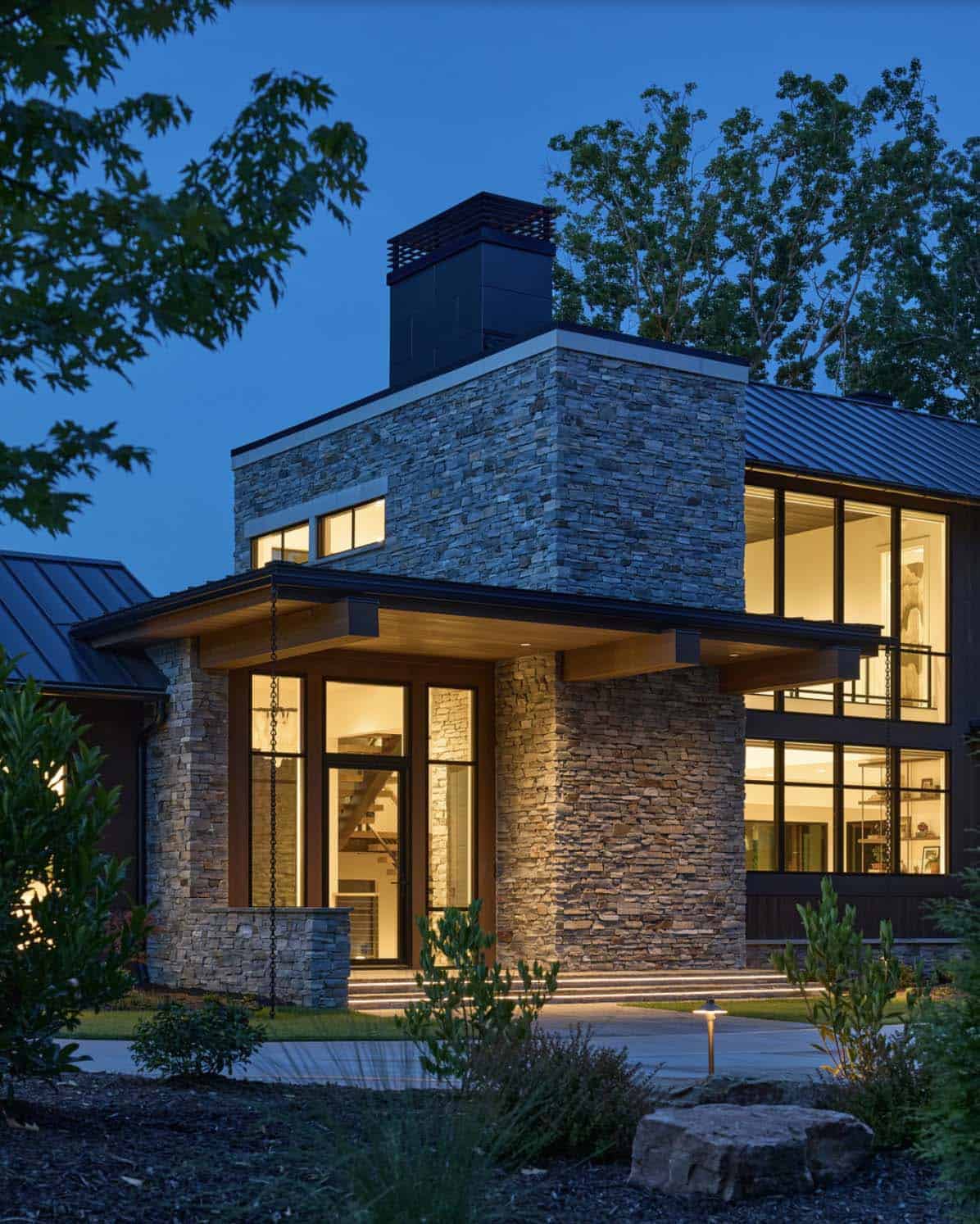 Nighttime close-up of the illuminated stone entry tower and glass-walled interior