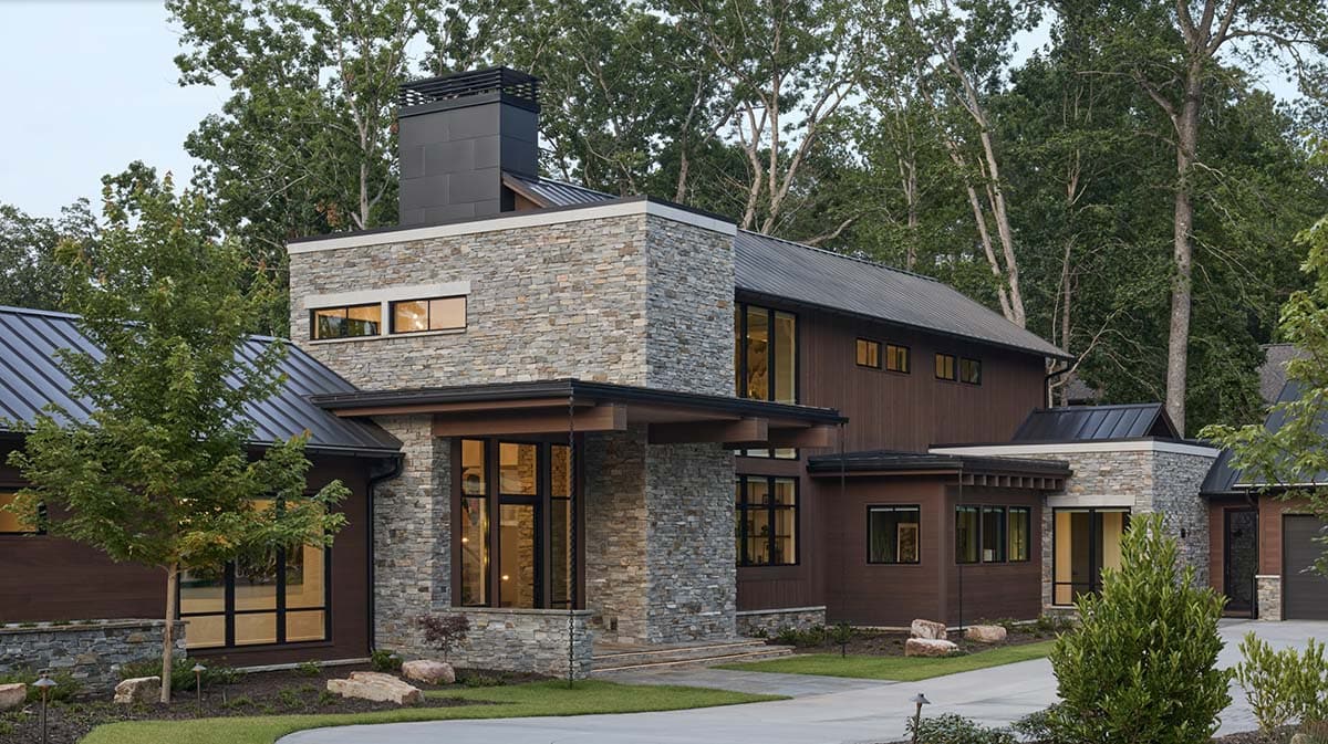 Evening exterior view of the stone entry tower and wood siding with landscape lighting
