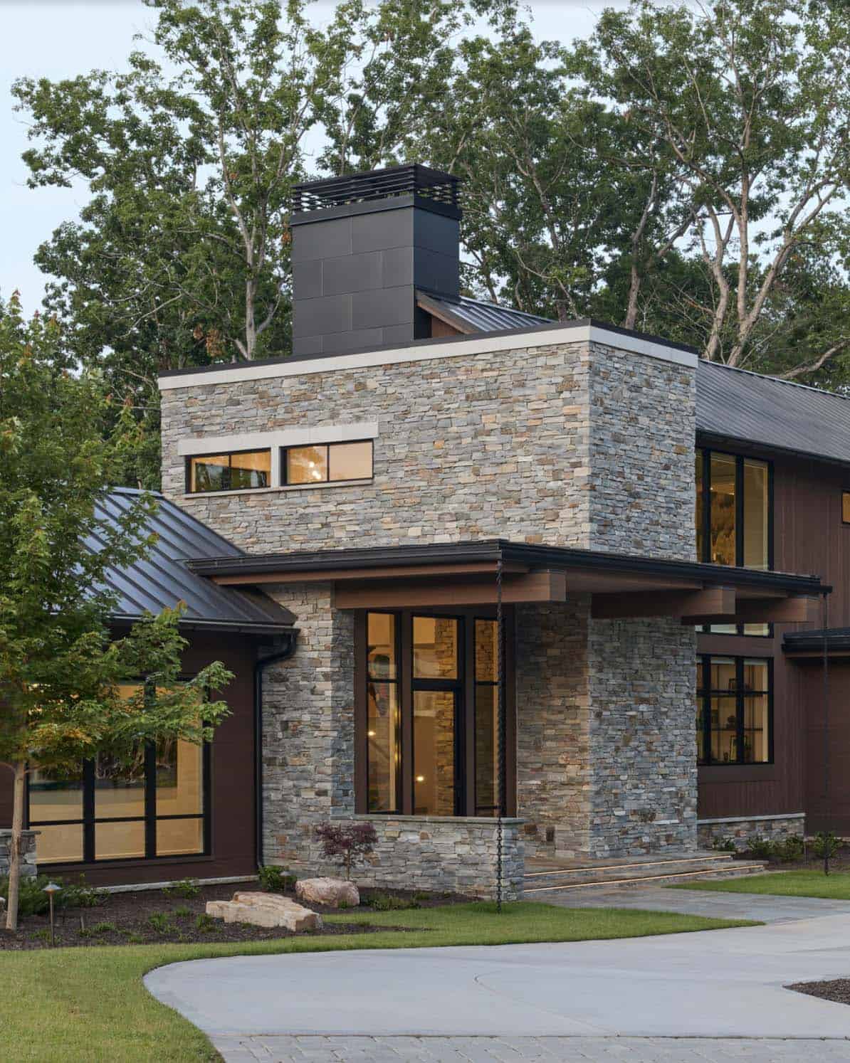 Twilight view of the stone entry tower with cantilevered wood roof and illuminated interior