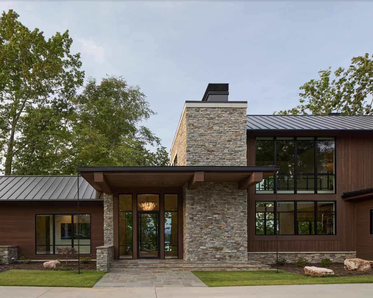 Front elevation showing entry tower, dark wood siding, and standing-seam metal roof at dusk