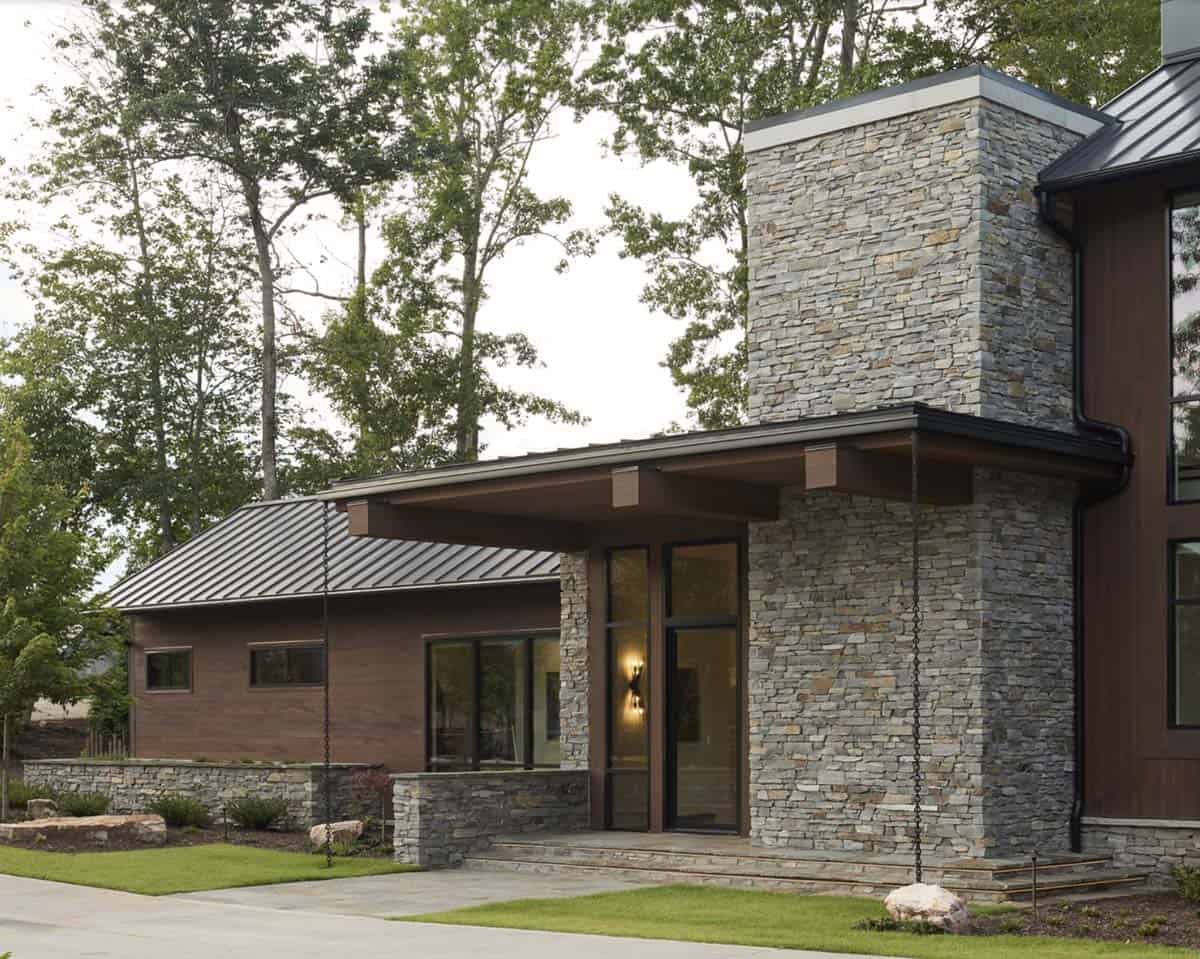 Close-up of stacked stone entry tower with covered porch and wall sconce lighting